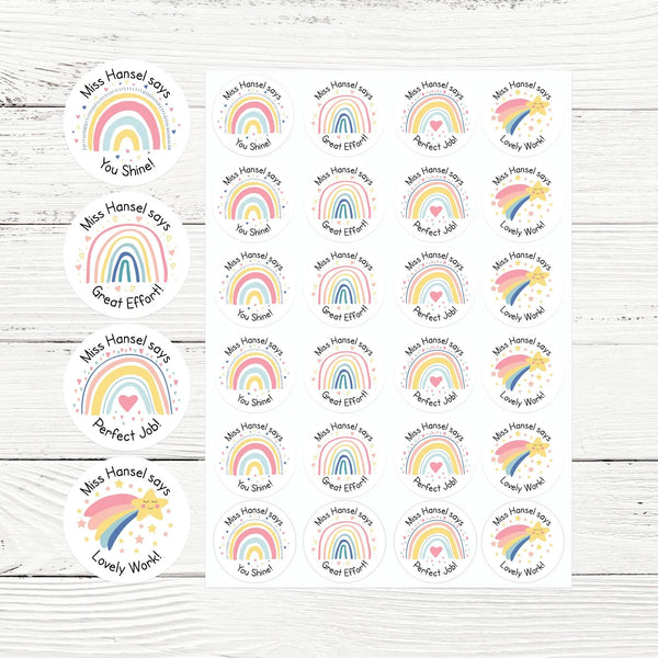 Sheet of round pastel rainbow teacher stickers with praise phrases on white wood background